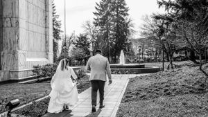 Black and white photo of a couple walking along a garden path near a stone building.