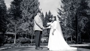 Black and white photo of a couple holding hands in a wooded outdoor setting.