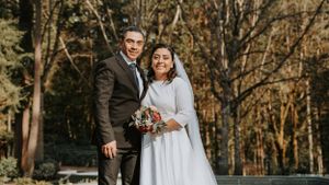 Outdoor wedding portrait with wooded background and natural lighting.