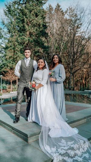 Wedding party portrait on concrete platform with evergreen and bare trees in background.