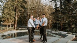 Wedding party posing together on marble steps outside elegant building.