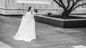 Bride in flowing white dress captured in black and white on stone terrace.