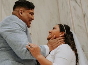 Wedding couple shares a joyful intimate moment while embracing against a white backdrop.