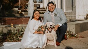Newlyweds smile with their golden retriever during outdoor wedding photoshoot.