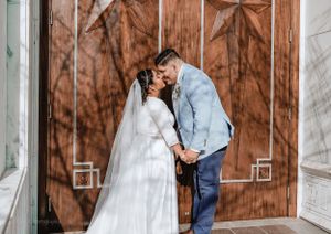 Couple shares intimate wedding moment in front of rustic wooden door with star decoration.