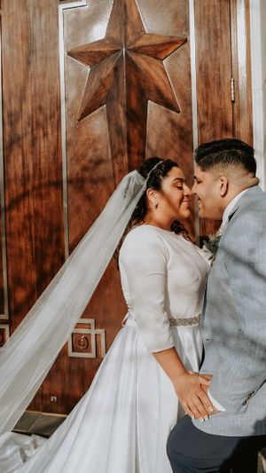 Romantic wedding portrait under decorative wooden star with bride's veil flowing elegantly.