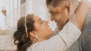 Romantic intimate moment between newlyweds in soft sunlit setting.