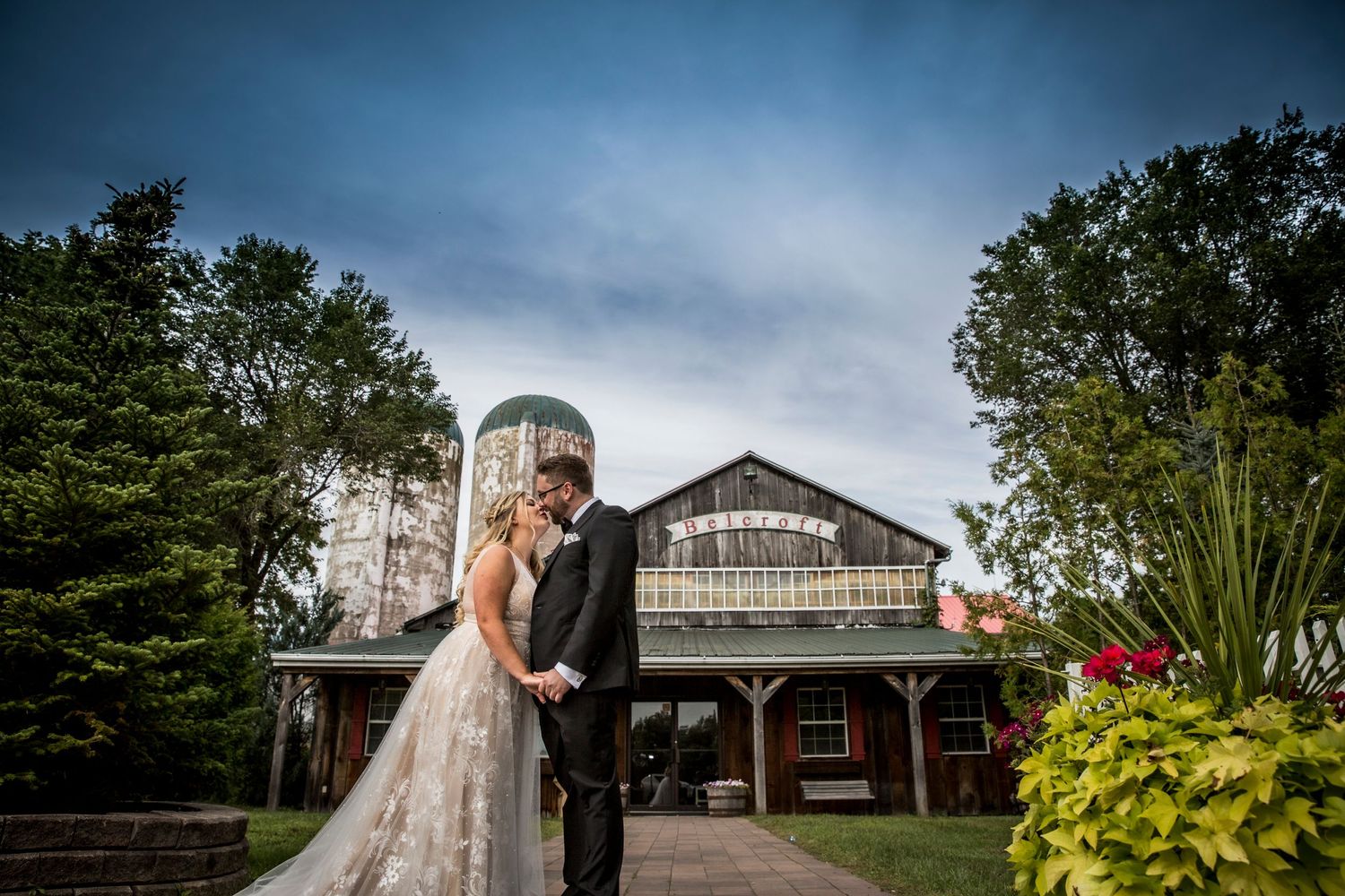 Wedding venue exterior with rustic barn buildings and landscaped gardens.