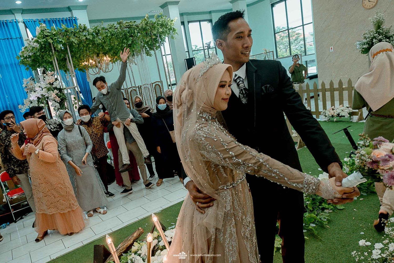 Couple dancing at their wedding reception surrounded by decorative floral arrangements and guests.