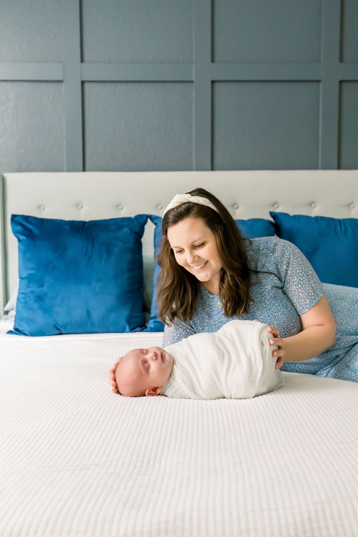 Sweet nurturing moment shared on a white bed with blue pillows in a peaceful bedroom setting.
