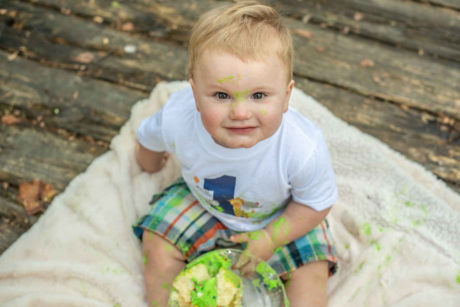 A baby plays with colorful paint during a messy outdoor art activity on wooden decking.