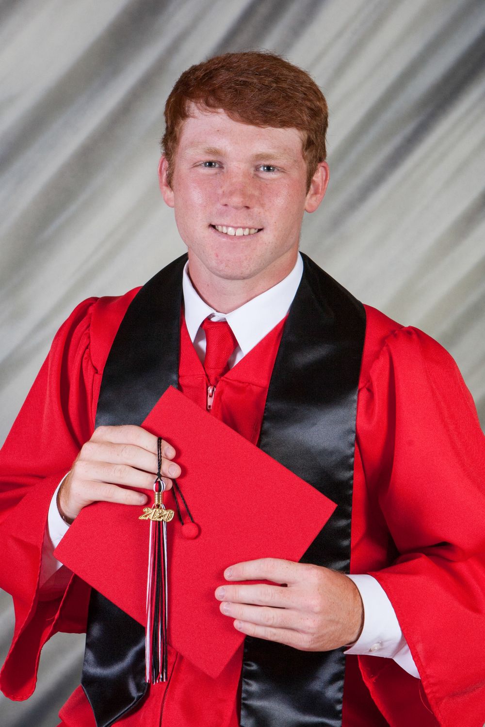senior boy in red and black cap and gown
