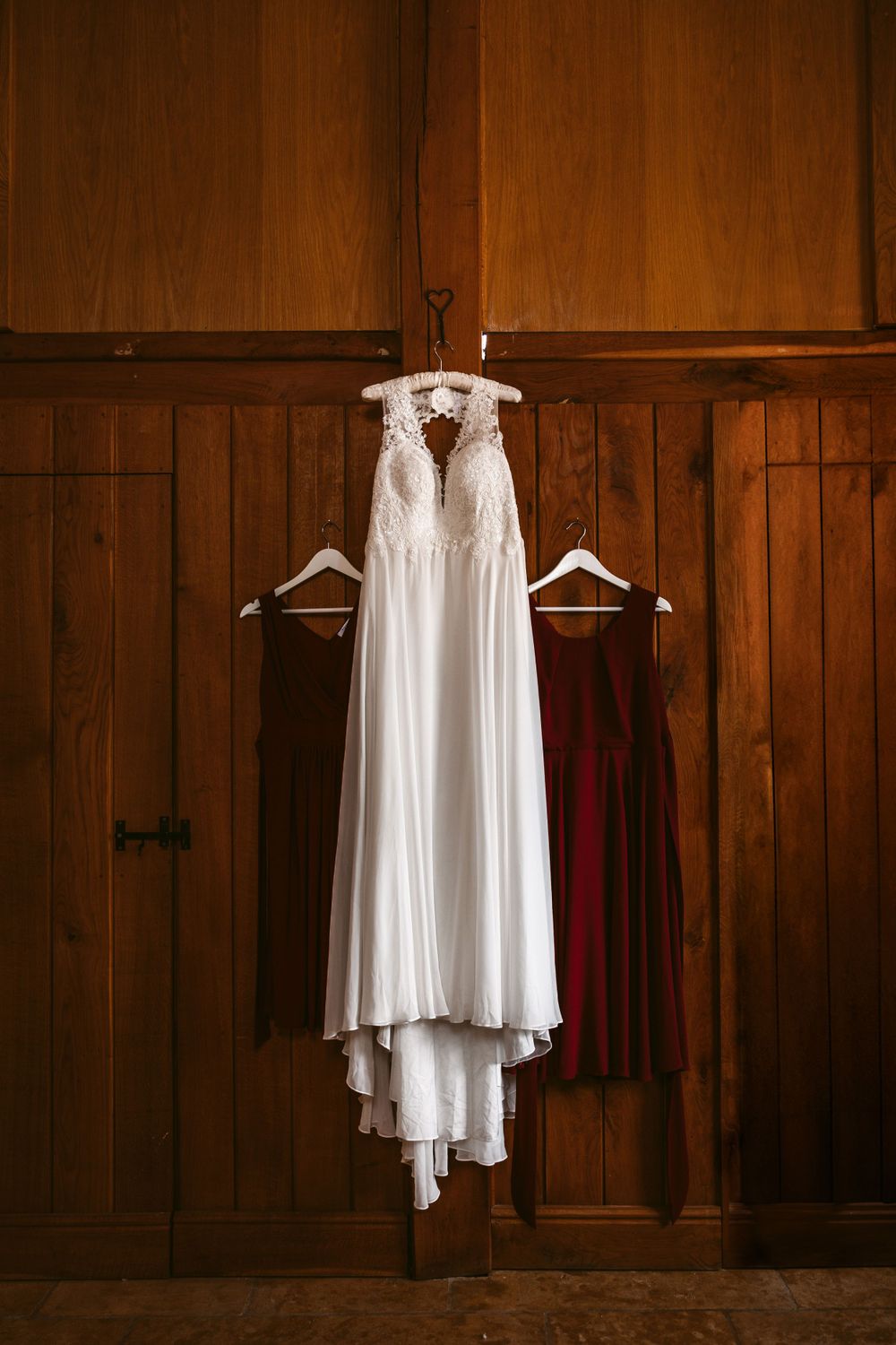 White lace wedding gown displayed on hanger against wooden panelled wall at Merriscourt.