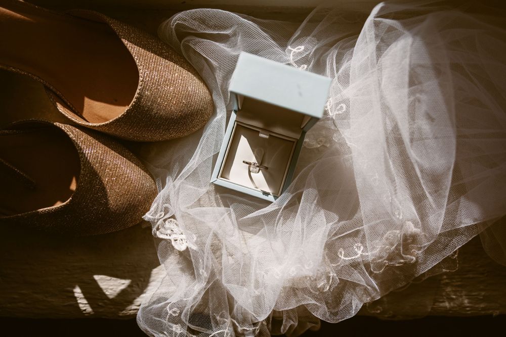 Wedding accessories including veil and shoes artistically arranged on dark wooden surface.