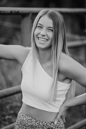 Black and white portrait of person in white tank top smiling outdoors.