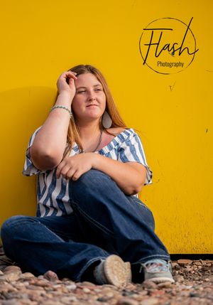 Portrait session against vibrant yellow wall with natural lighting and casual poses.