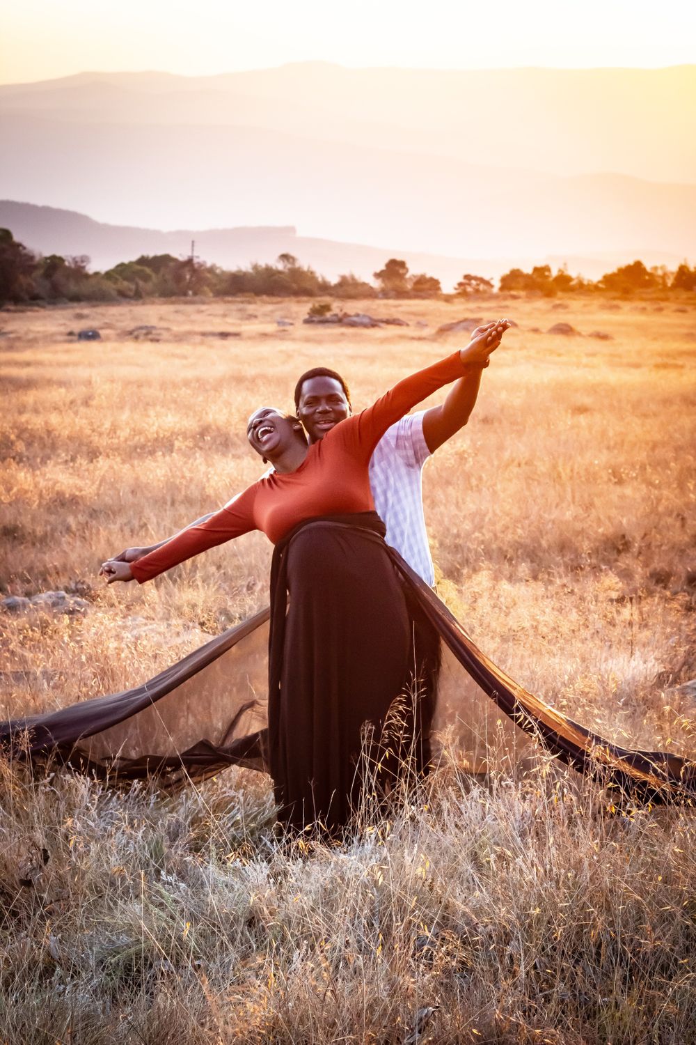 couple dancing in field pregnant woman laughing maternity dress sunset happy love