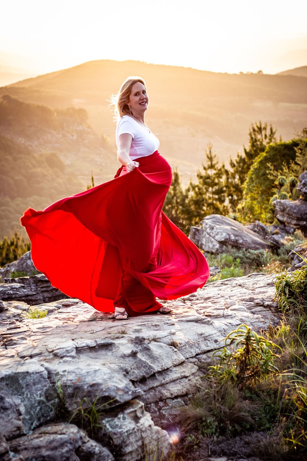 pregnant woman maternity dress wind blowing hair blonde valley background sunset red cliff