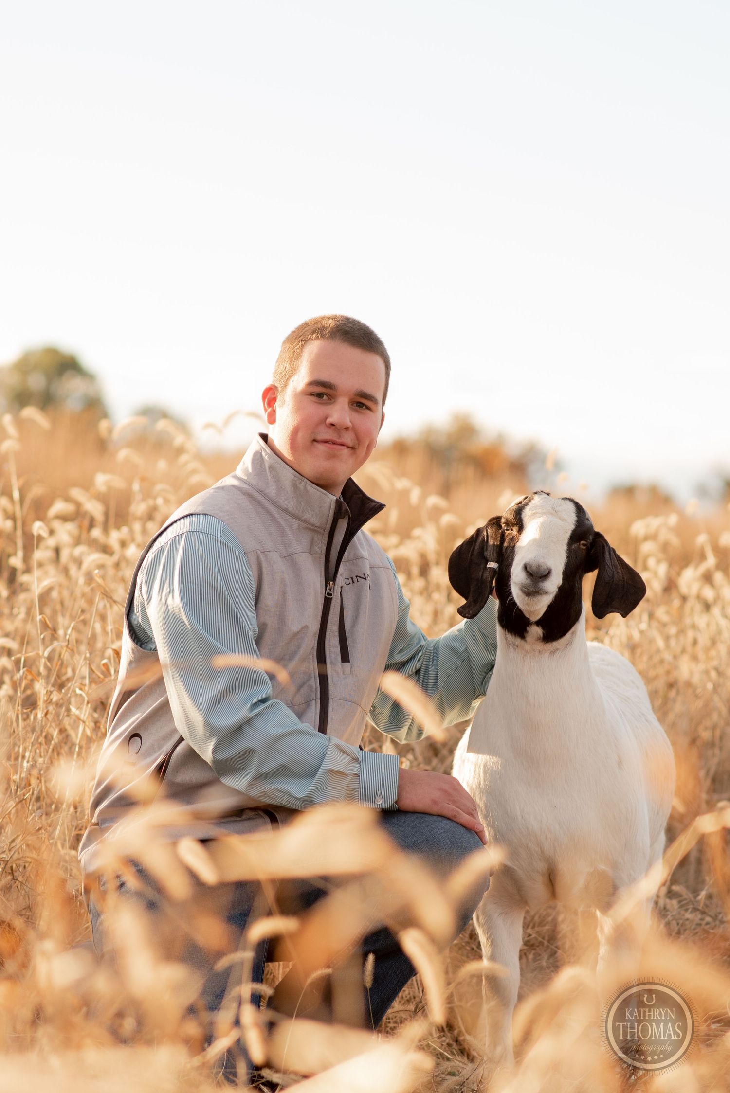 Person and Boer goat pose together in sunlit field of tall autumn grass.