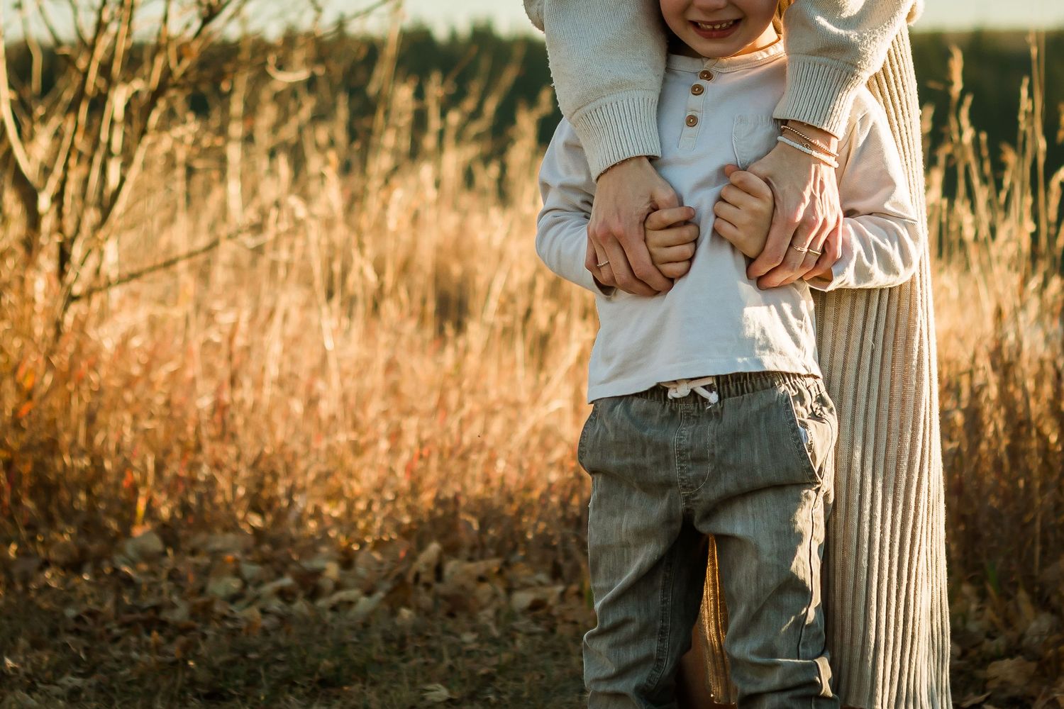 Beautiful authentic lifestyle family photography at golden hour in long grass in Calgary AB.