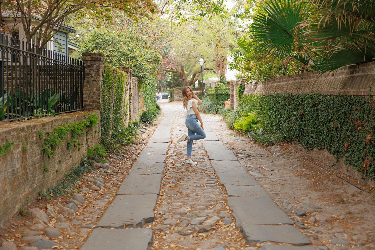 Person walking down historic cobblestone path lined with ivy covered walls.