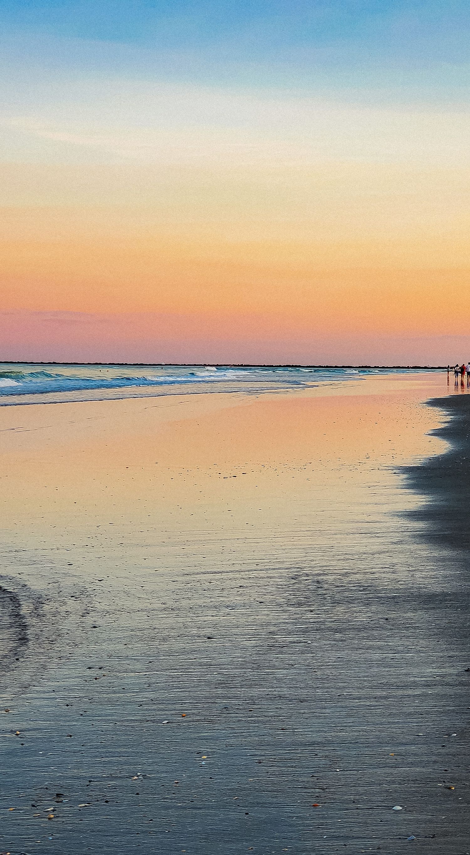 Serene beach landscape with pastel sunset colors reflecting on wet sand.