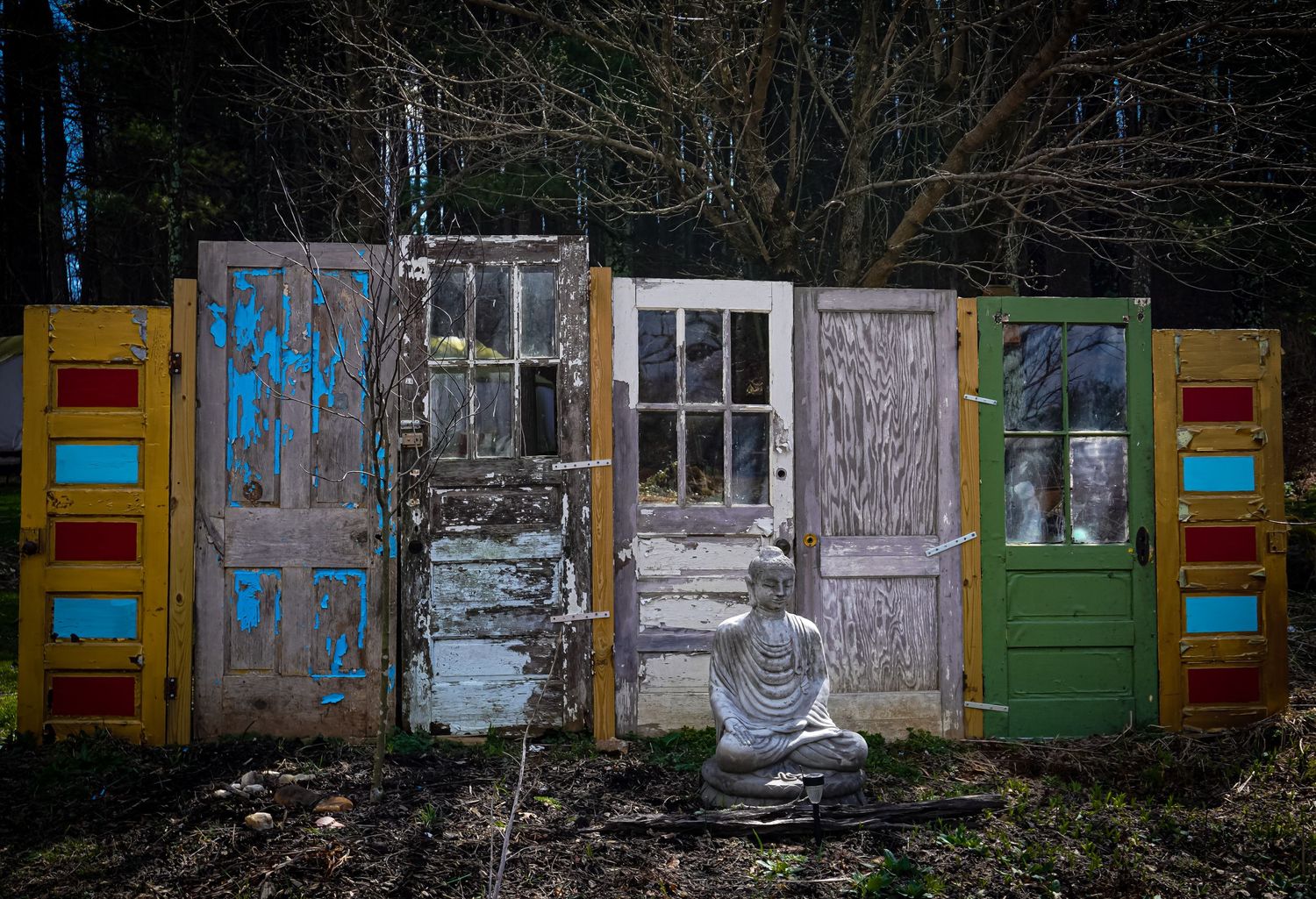 Collection of weathered vintage doors arranged outdoors with peeling paint and graffiti.