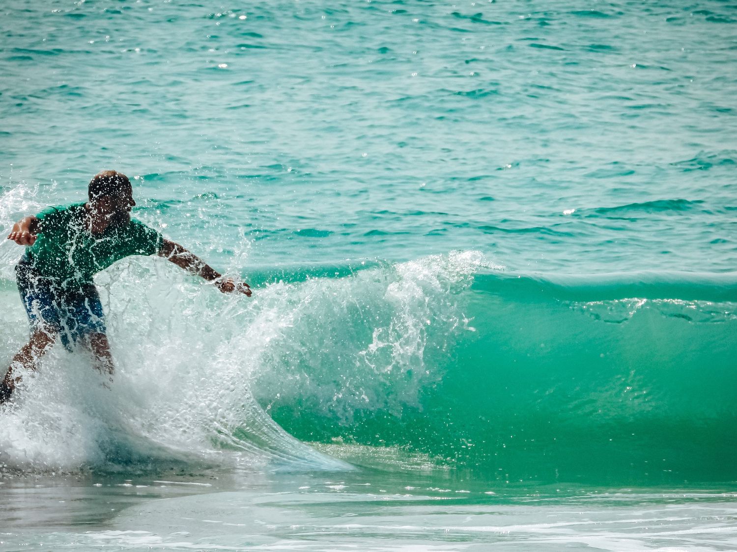 Surfer catching a wave on turquoise waters with dramatic splash.
