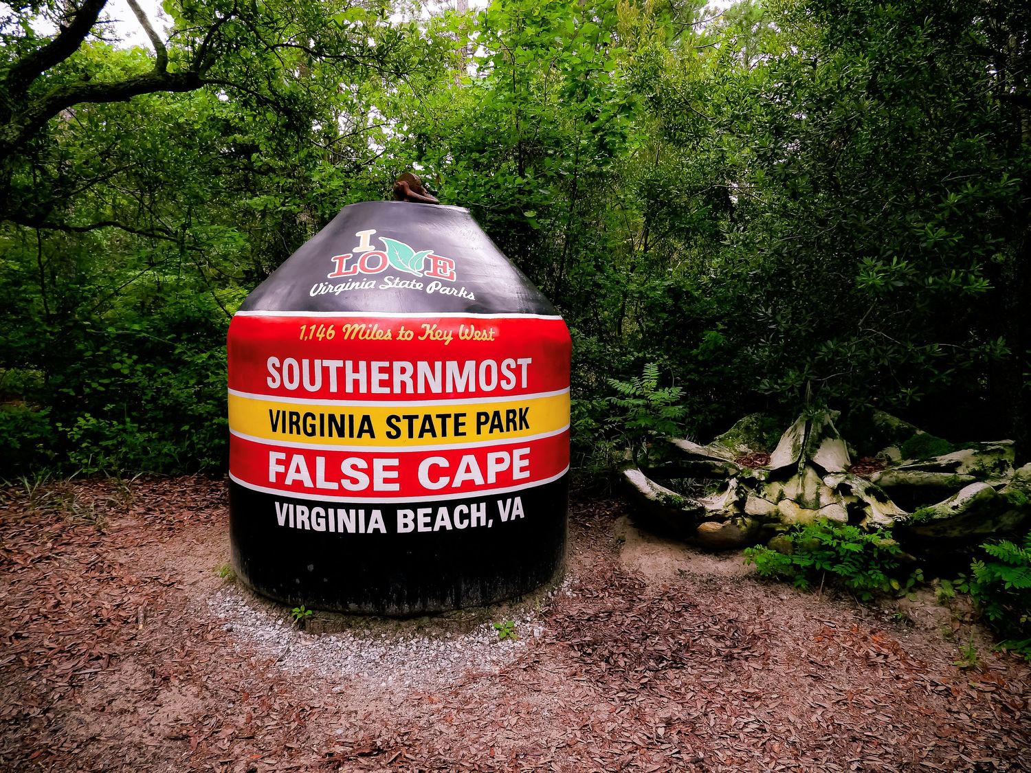 Large buoy marker for Southernmost Virginia State Park False Cape along a wooded trail.