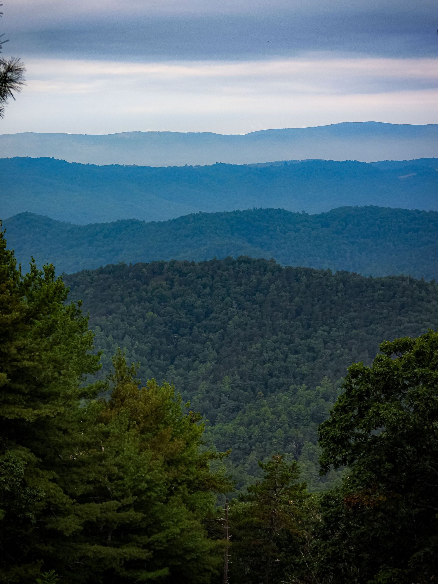 Rolling blue mountain ridges create layers of misty hills stretching to the horizon.