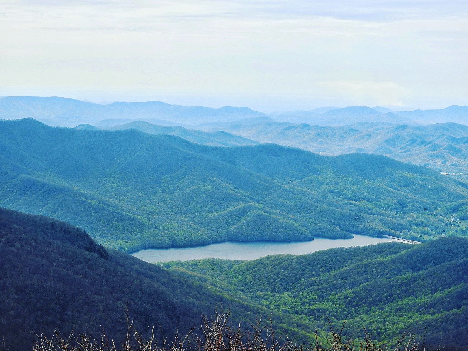 Aerial view of a serpentine lake surrounded by blue-tinted mountain ridges.