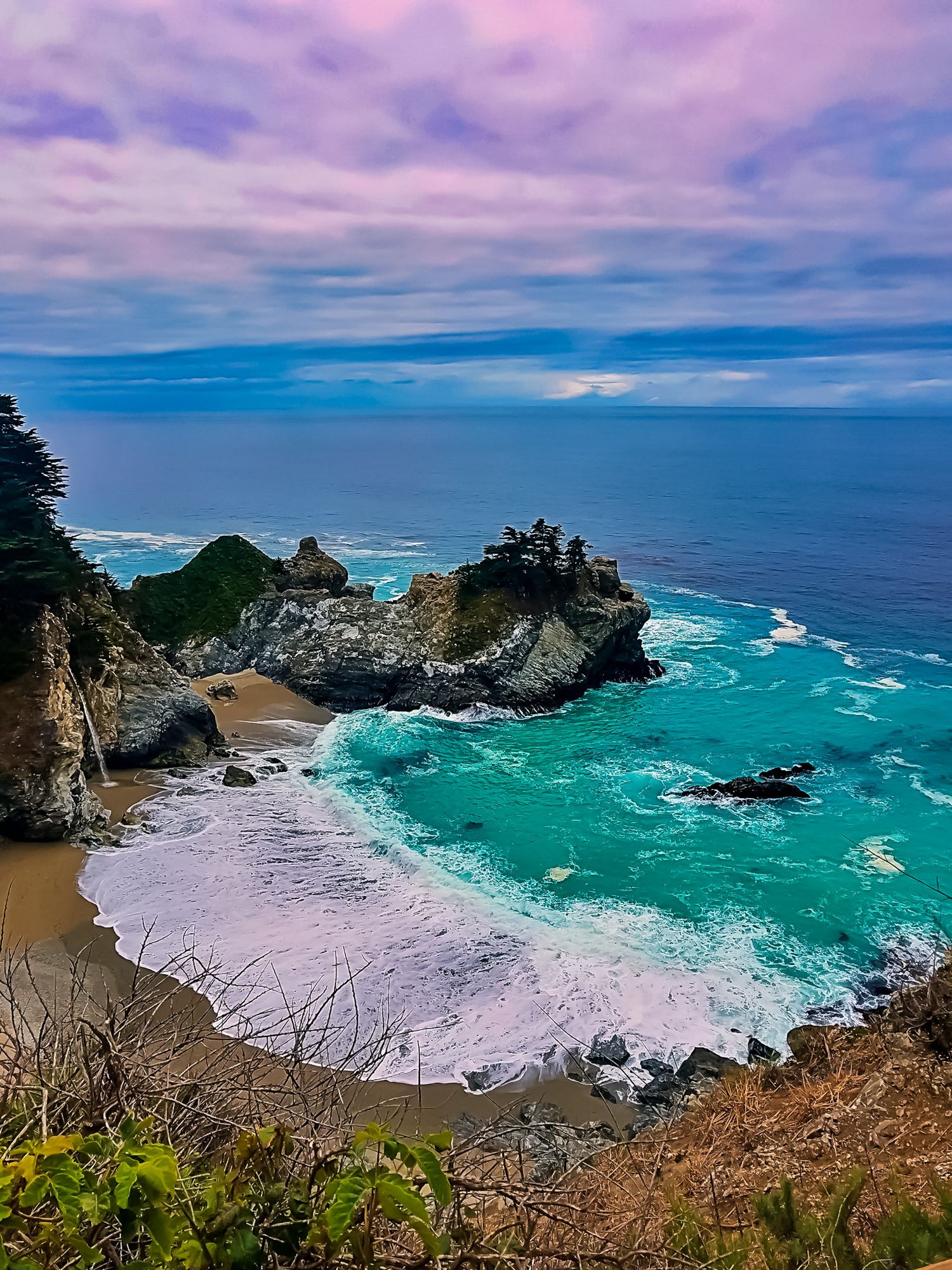 Dramatic coastal cove with turquoise waters and rocky cliffs at McWay Falls in Big Sur, California.