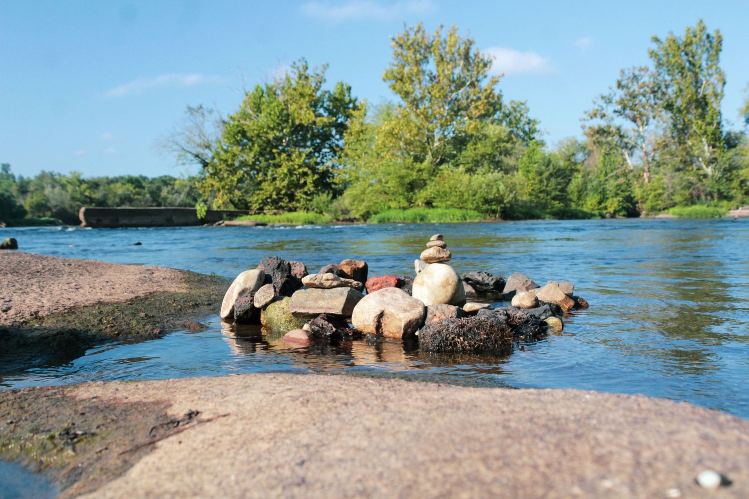 Stone circle arrangement in shallow river waters during golden hour.
