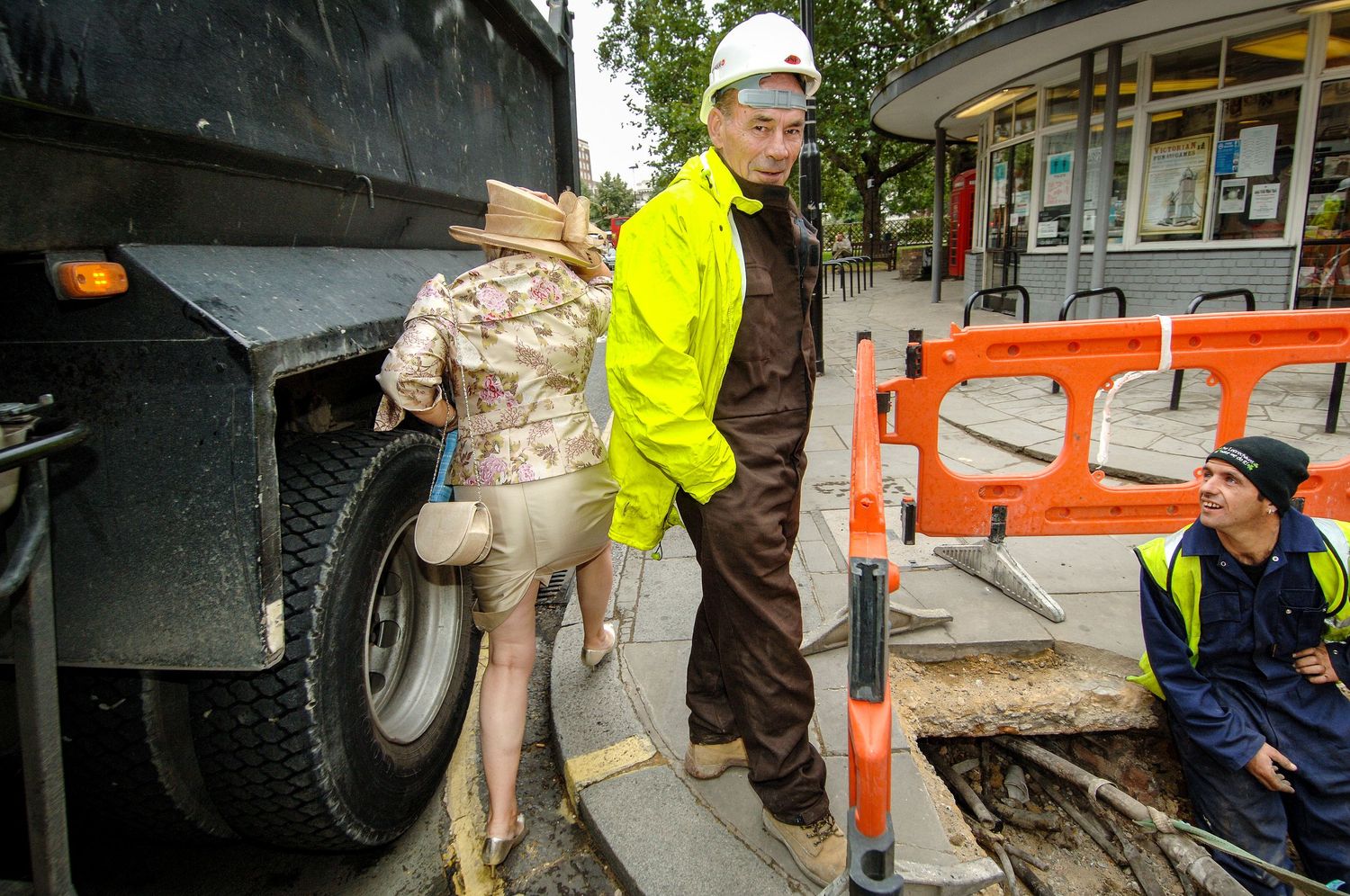 mother of the bride squeezes past a workman as she hurries to the wedding