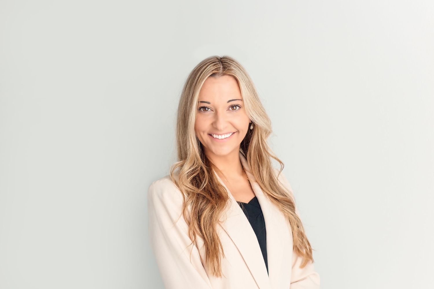 A professional headshot of a person in a cream blazer against a light background.