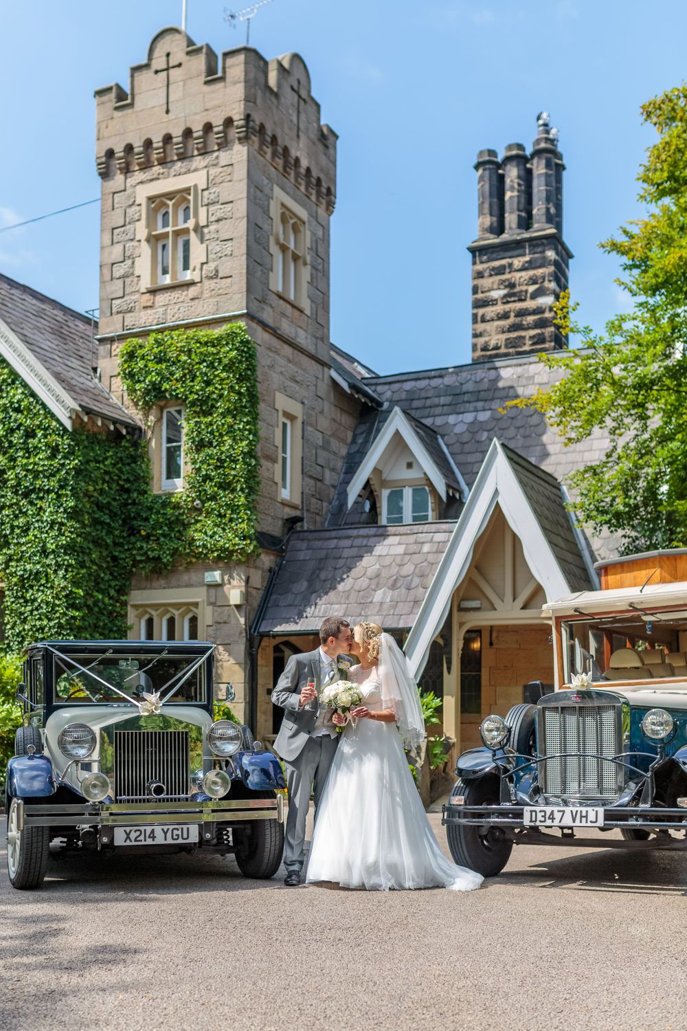 bride and groom pose kissing alongside the wedding cars at the front of west tower exclusive wedding venue