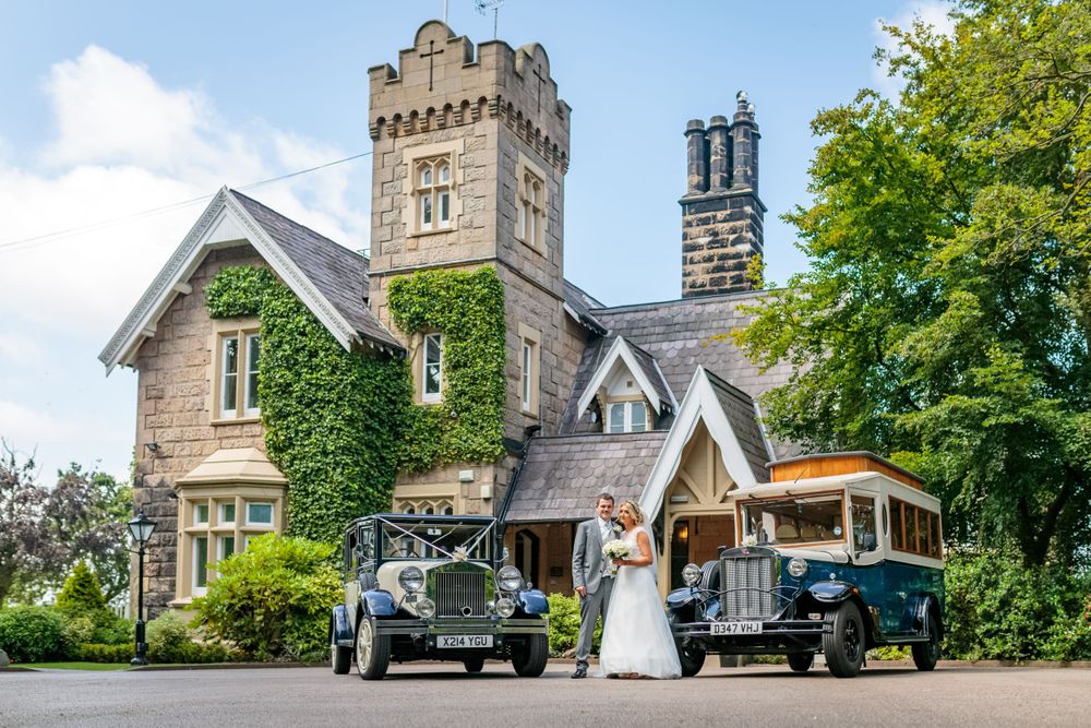 wide shot of the bride and groom posing with the wedding cars outside the front of west tower ormskirk