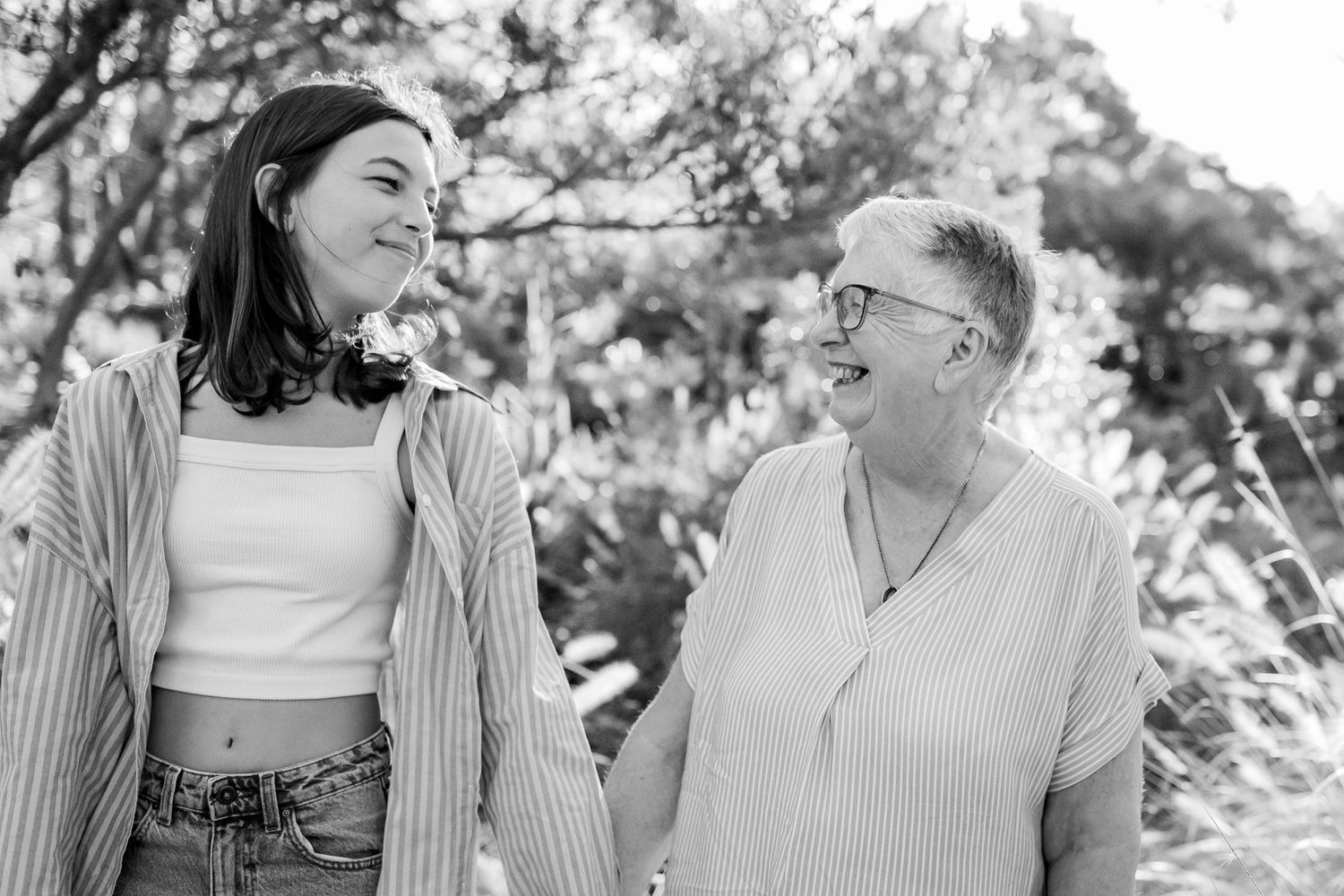 Black and white portrait of two people sharing a joyful moment on an outdoor path.