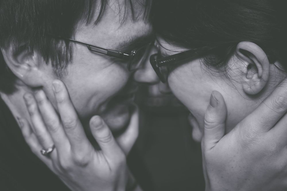 A black and white intimate portrait of a couple in close embrace.
