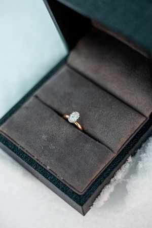 Diamond engagement ring in a dark velvet box photographed from above.