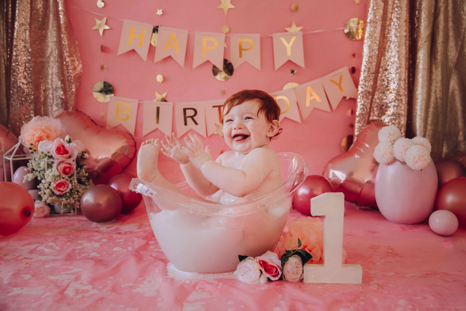 Pink birthday party setup with balloons, decorations and teddy bears against a rosy backdrop.