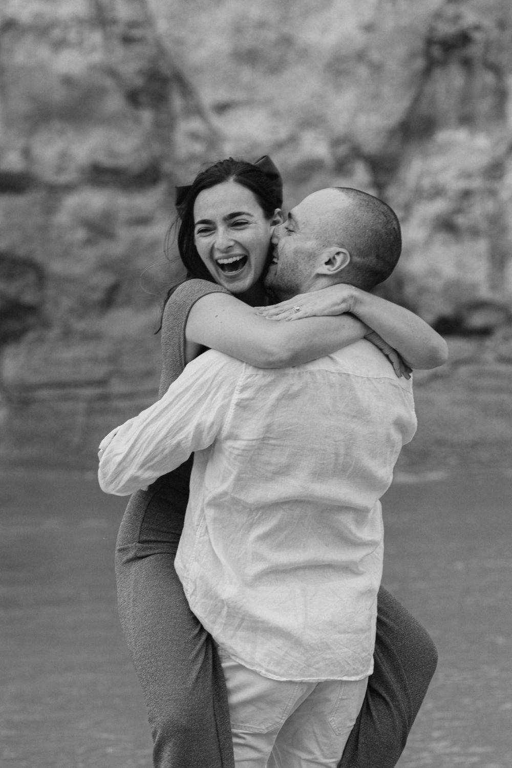 Man lifting his partner in an affectionate moment during a seaside engagement session.