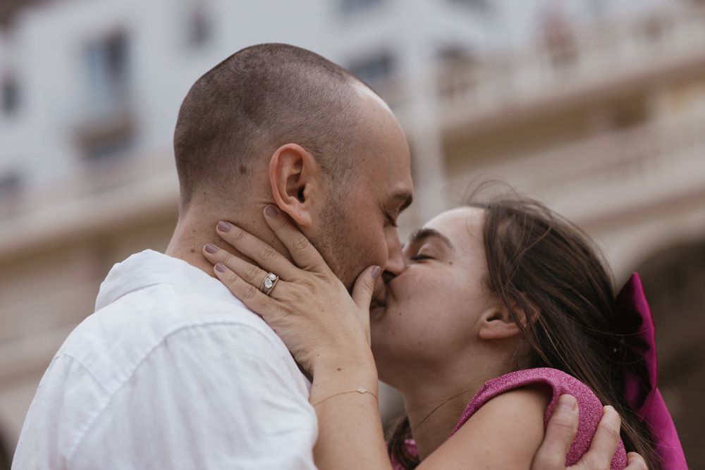 Couple sharing a kiss by dramatic coastal rocks during a cinematic engagement photoshoot.