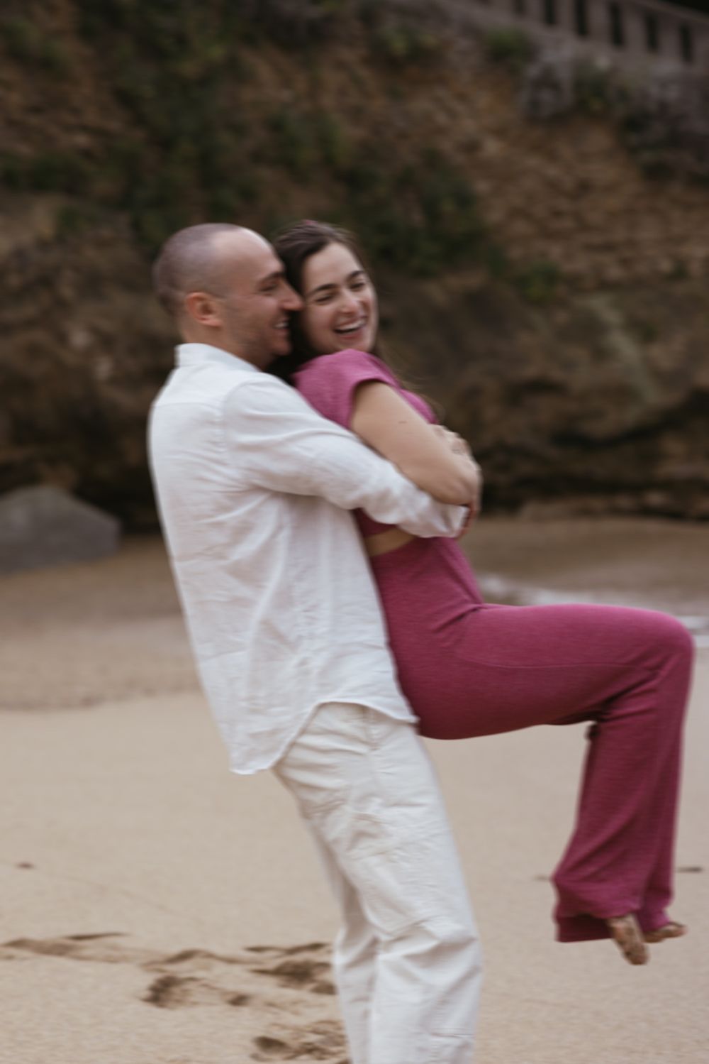 Blurred motion portrait of couple embracing by the shoreline, captured with fine-art film tones.