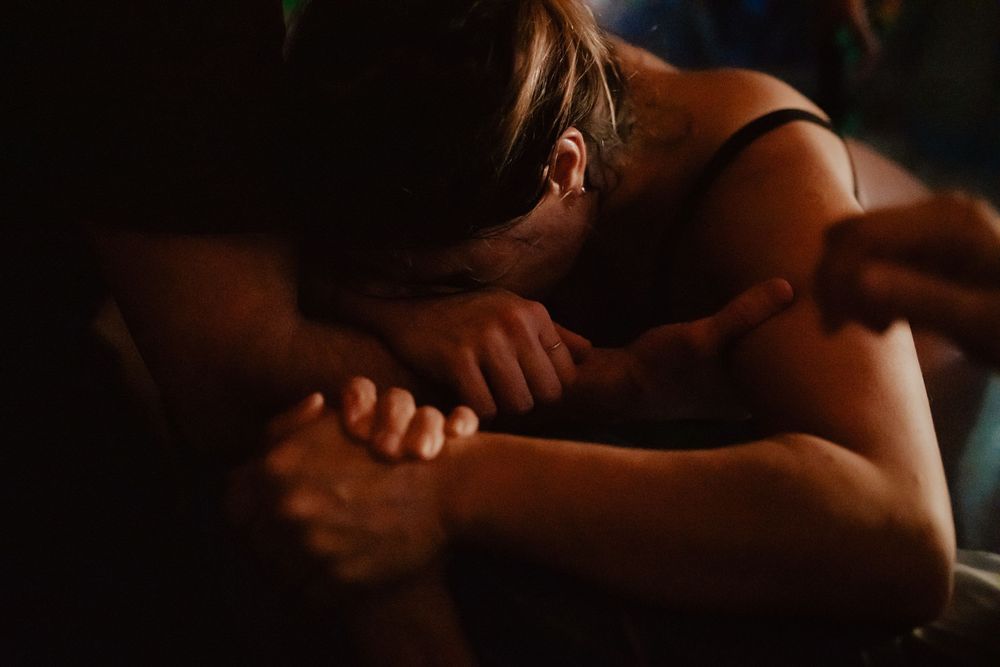 Dark and moody portrait of intimacy with soft shadows.