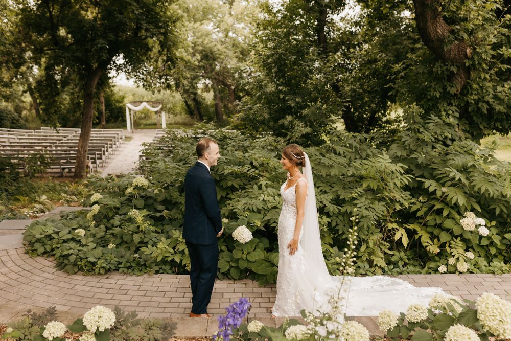Bride and groom facing each other during emotional first look in garden setting.