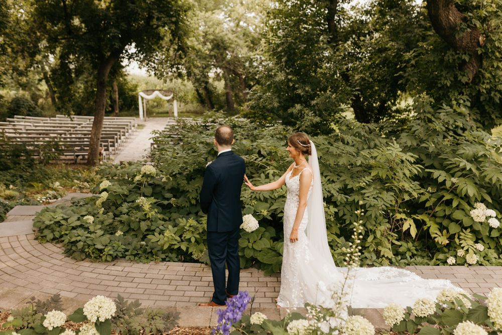 Bride and groom holding hands while walking through lush green garden wedding venue.