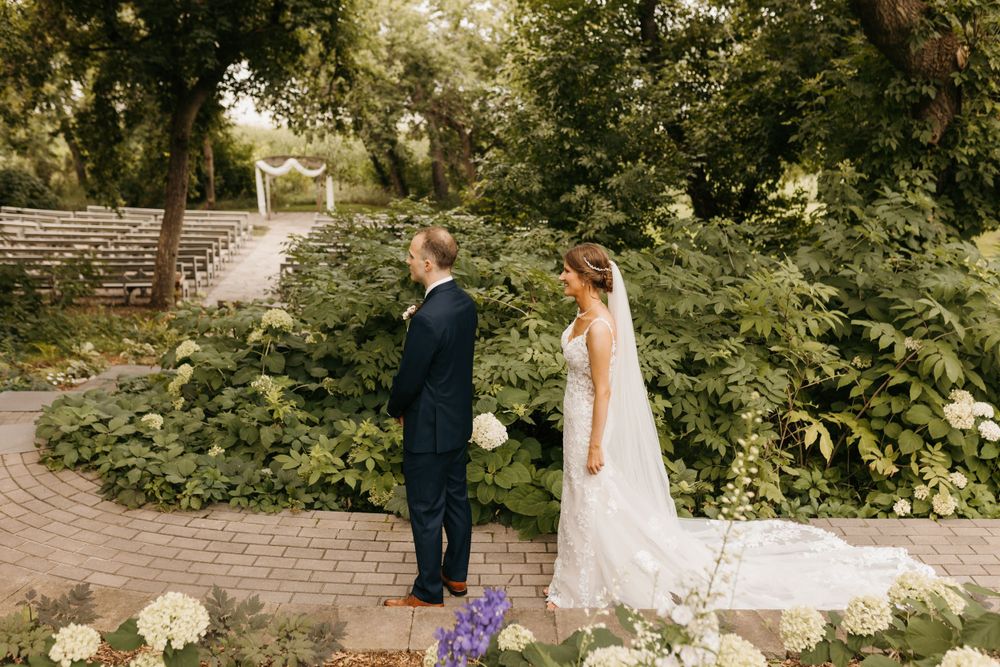 Bride and groom sharing first look moment in lush garden wedding venue.
