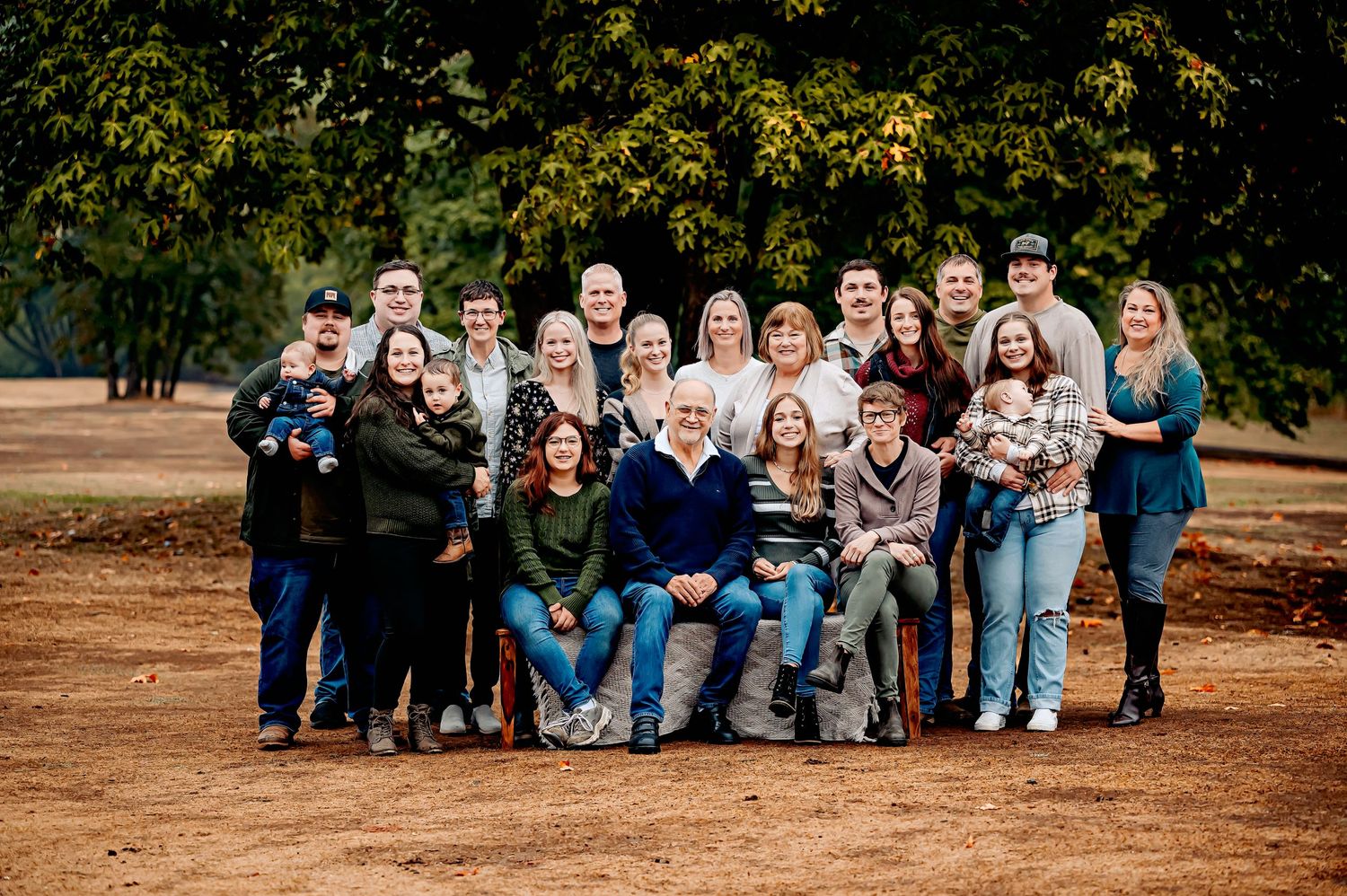 Large family group photo taken outdoors in casual clothing during autumn.