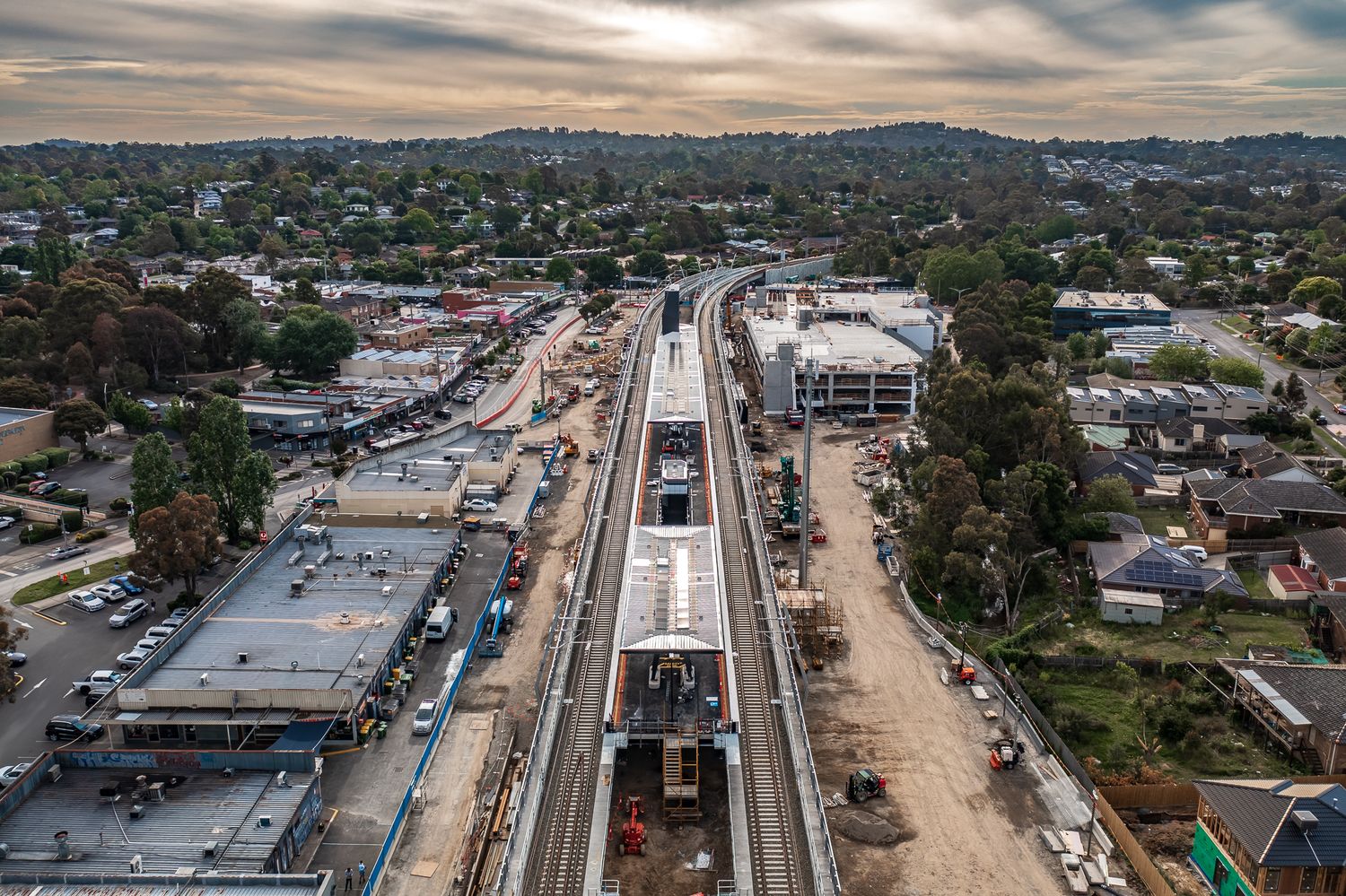 Aerial view of nearly complete elevated railway station surrounded by suburban Australian residential development.